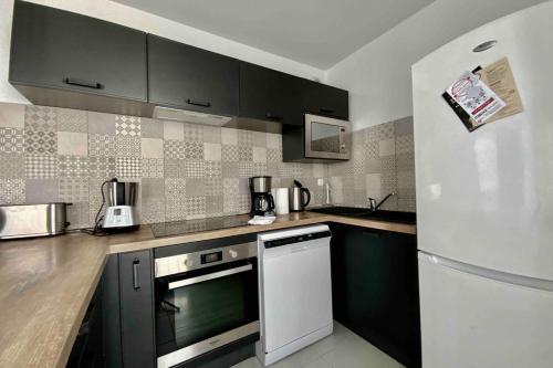- une cuisine avec des armoires noires et un réfrigérateur blanc dans l'établissement The Pleasant - Air conditioning terrace and parking!, à Montpellier