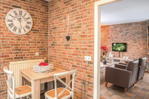 a brick wall with a clock and a table and chairs at 't Borghuis in Losser