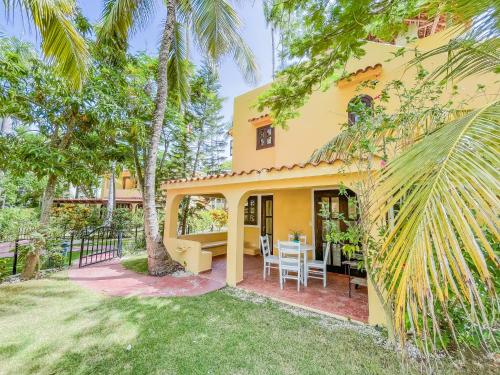 una casa amarilla con una mesa y sillas en un patio en Villas & Apartments OCEAN & GARDEN VIEW Vacation HOTEL RENTALS Long Term BAVARO Los Corales, en Punta Cana