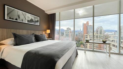a bedroom with a large bed and large windows at Hotel Capital Bellet in Santiago