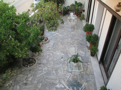 a patio with tables and chairs and potted plants at NICK STUDIOS previous NICK HOUSE in Plomarion