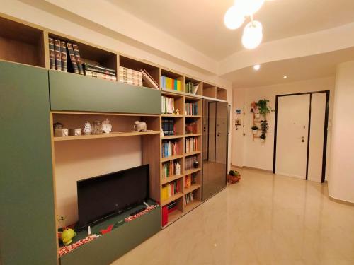ein Wohnzimmer mit Bücherregalen und einem Flachbild-TV in der Unterkunft A casa di Carola. Appartamento in centro dove sentirsi a casa in Molfetta
