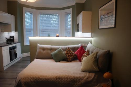 a bed with pillows on it in a room with windows at Julia's place in Hoylake