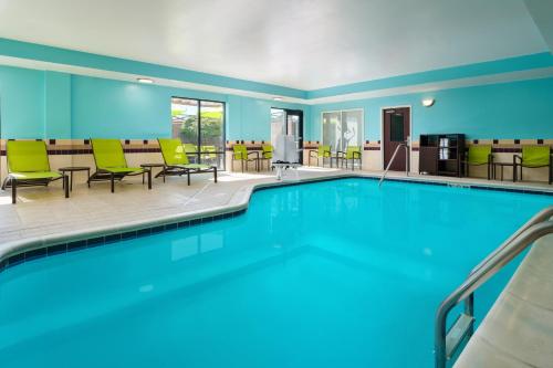 a pool in a hotel room with chairs and tables at SpringHill Suites Richmond Northwest in Richmond