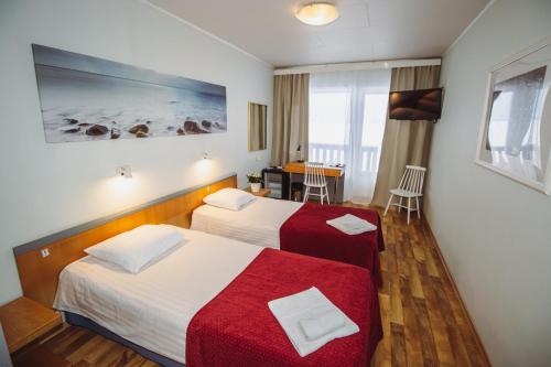 a hotel room with two beds and a table at Hotel Promenaadi in Haapsalu