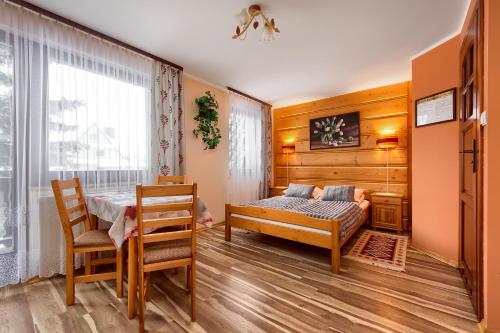 - une chambre avec un lit, une table et des chaises dans l'établissement Willa Bartek, à Zakopane