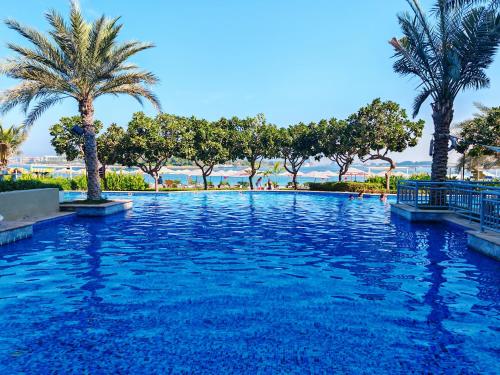 a swimming pool with palm trees in a resort at Seaside Serenity Residence Elegant 1BR Escape in Palm Jumeirah by La Buena vida holiday homes in Dubai