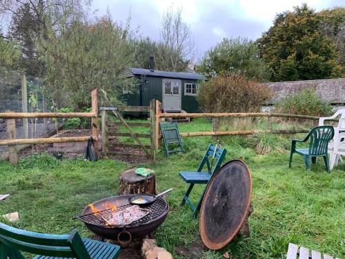 a backyard with a grill and chairs and a fence at Rushford Shepherd's Hut in Newton Abbot