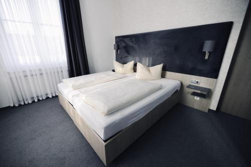 1 dormitorio con 1 cama blanca grande y cabecero negro en N9 Hotels en Núremberg