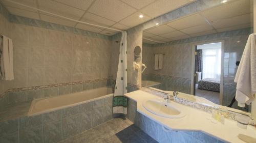 uma casa de banho com 2 lavatórios, uma banheira e um espelho. em Hotel Shipka em Golden Sands