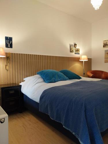 a bedroom with a large bed with blue pillows at B&B Noordwijk Binnen in Noordwijk