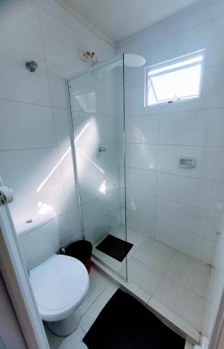 a bathroom with a toilet and a glass shower at Guarujá Praia Hotel Econômico in Guarujá