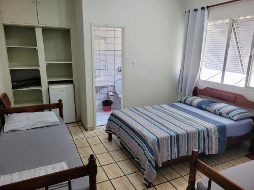 a bedroom with a bed and a table and a window at Guarujá Praia Hotel Econômico in Guarujá