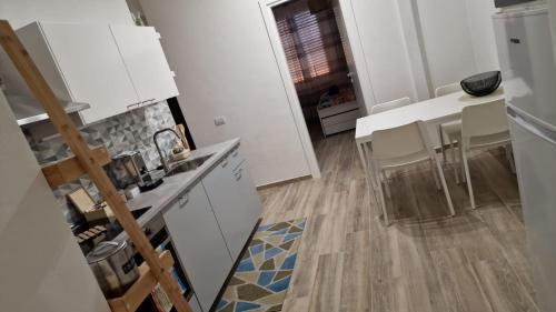 uma cozinha com armários brancos e uma mesa e cadeiras em Appartamento Violet - Parma em Parma
