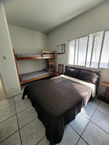 a bedroom with a bed in a room with windows at Guarujá Praia Hotel Econômico in Guarujá