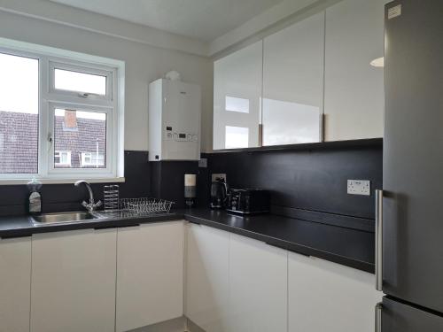 a kitchen with white cabinets and a black counter top at Lovely 2-Bed Apartment in Cheltenham Spa in Cheltenham