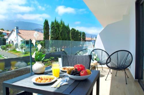 una mesa con platos de comida en el balcón en Modern Oasis - Pool, Gym & Tennis, en Puerto de la Cruz