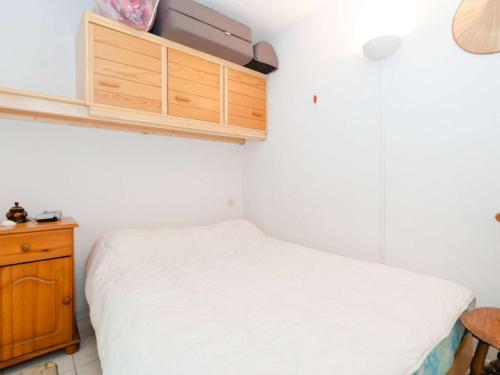 une chambre avec un lit blanc et une armoire en bois dans l'établissement Appartement T2 en Rez-de-Jardin, Front de Mer, 4 pers. - Narbonne-Plage - FR-1-409-62, à Narbonne-Plage