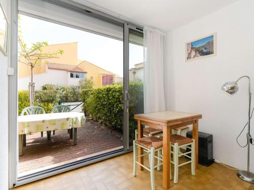 une porte coulissante en verre menant à une terrasse avec une table. dans l'établissement Appartement T2 en Rez-de-Jardin, Front de Mer, 4 pers. - Narbonne-Plage - FR-1-409-62, à Narbonne-Plage