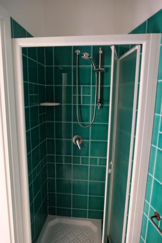 ein grün gefliestes Bad mit einer Dusche und einer Badewanne in der Unterkunft Calarossa Sardinia Apartments in Isola Rossa