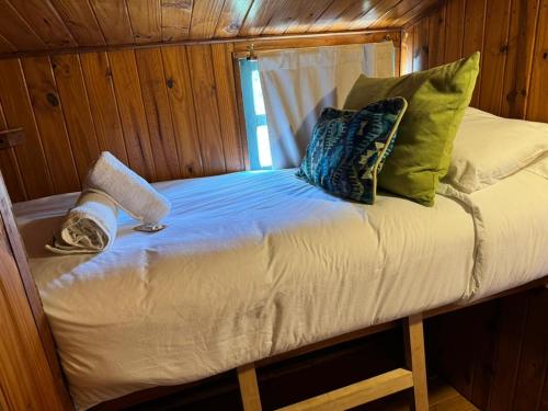 ein kleines Bett in einer Holzhütte mit Kissen in der Unterkunft Complejo Como Vaca in El Chalten