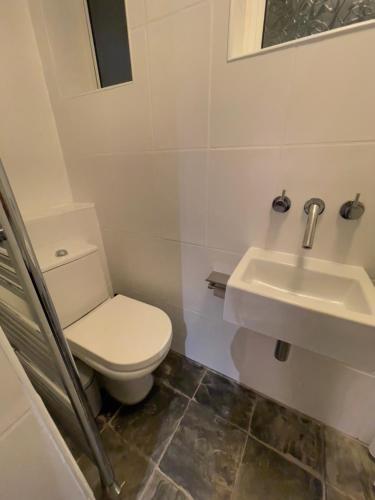 y baño con aseo y lavamanos. en London Townhouse 1-Bed Apartment with Garden in Tufnell Park near Emirates Stadium and 10 mins to Kings Cross en Londres