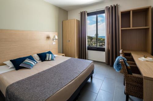 um quarto com uma cama, uma secretária e uma janela em Les appartements de l'Helios - Ile des Embiez em Six-Fours-les-Plages