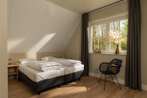 a bedroom with two beds and a chair and a window at 't Borghuis in Losser