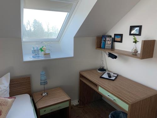 a bedroom with a bed and a desk and a window at Circus Hostal Putbus in Putbus