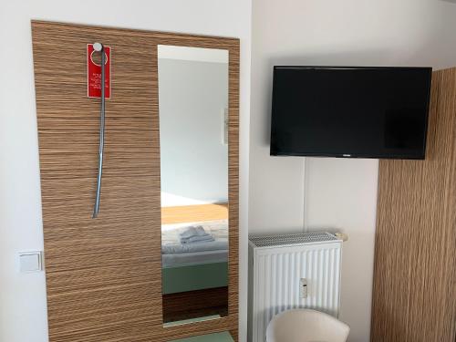 een kamer met een deur met een spiegel en een tv bij Circus Hostal Putbus in Putbus