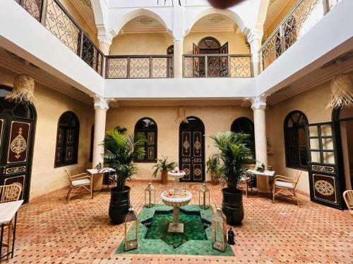 a large lobby with a table and palm trees at Riad Bamaga in Marrakesh