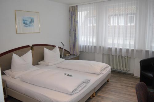 1 dormitorio con 1 cama con sábanas y almohadas blancas en Boardinghaus zu Coburg, en Coburg