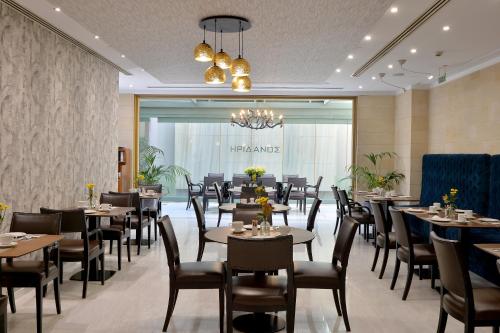 a restaurant with tables and chairs and a chandelier at Athenaeum Eridanus Luxury Hotel in Athens