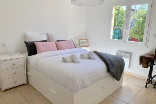 a white bed with pink and grey pillows on it at La tranquillle - Villa with garden in Montpellier! in Montpellier