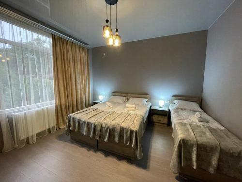 a bedroom with two beds and a large window at Hotel Lumi in Zugdidi