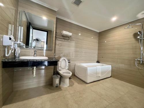 łazienka z toaletą, umywalką i wanną w obiekcie Grand Dragon Noi Bai Hotel w mieście Hanoi