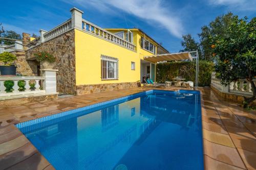 ein Pool vor einem Haus mit einem gelben Haus in der Unterkunft Villa Vista Lux, Piscina privada y zona exterior con vista Mar in Tossa de Mar