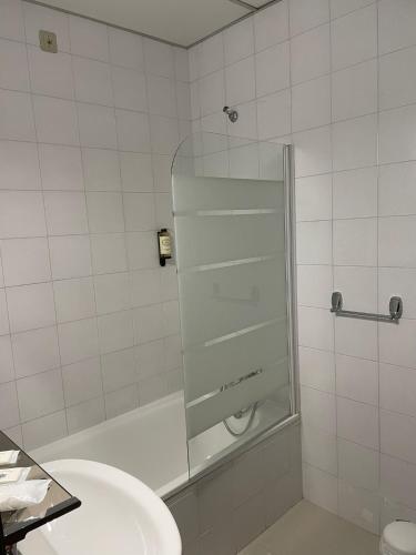 a bathroom with a shower and a white sink at Flag Hotel Madeira - Ribeira Brava in Ribeira Brava
