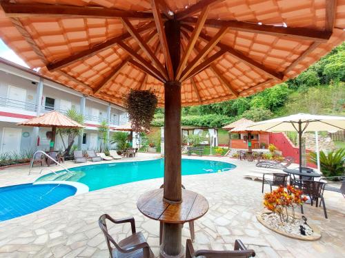 a patio with an umbrella and a swimming pool at Pousada Pompeia in Socorro
