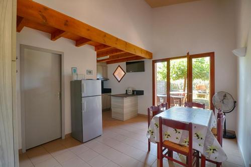 une cuisine et une salle à manger avec une table et un réfrigérateur dans l'établissement Appartement n1 rez de jardin LA LISCIA, à Calcatoggio