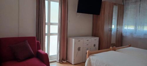 a bedroom with a bed and a chair and a window at Apartments Villa Split Podstrana in Podstrana