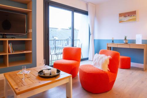 un salon avec deux chaises orange et une table dans l'établissement 350m plage de la Cale de Beg Meil, cocon pour 2, à Fouesnant