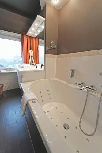 a bathroom with a tub and a sink at Hôtel Panorama - Vue exceptionnelle sur la Semois in Bouillon