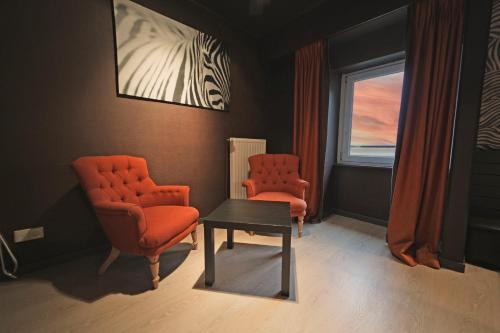 two orange chairs and a table in a waiting room at Hôtel Panorama - Vue exceptionnelle sur la Semois in Bouillon