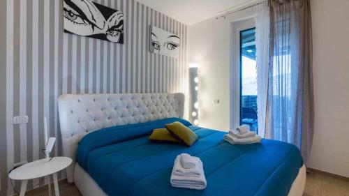 a bedroom with a blue bed and a table and a window at PiscinaParkingVista Mare La Perla Ligure AC in Pietra Ligure