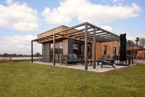 a pavilion with chairs and a table in a field at Hofparken De Bergvennen in Lattrop