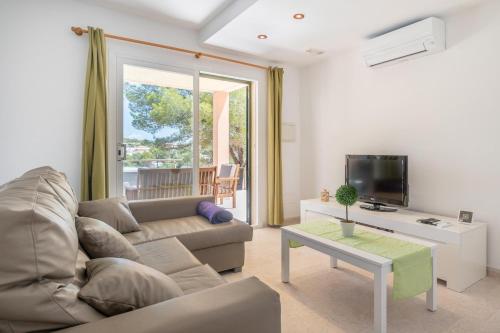 een woonkamer met een bank en een tv bij Cala Mendia Beach House 1 by Slow Villas in Cala Romantica