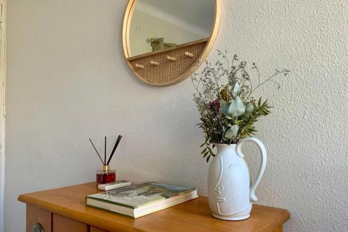 eine Vase aus Blumen auf einem Tisch mit einem Spiegel in der Unterkunft La Poétique - Air-conditioned house with 3 bedrooms! in Montpellier