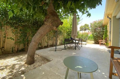 a table and a chair next to a tree at La Poétique - Air-conditioned house with 3 bedrooms! in Montpellier