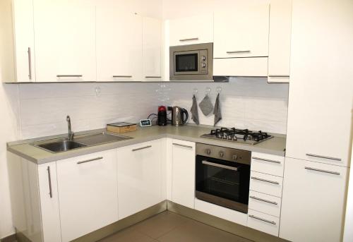 eine weiße Küche mit einer Spüle und einer Mikrowelle in der Unterkunft Villa Costanza in Bari